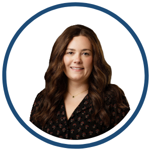 Headshot of Abby Barker, Area Director at Mosaic A headshot of Abby Barker, a woman with long wavy brown hair, wearing a black patterned blouse. She is smiling softly and is framed within a circular navy border on a white background.